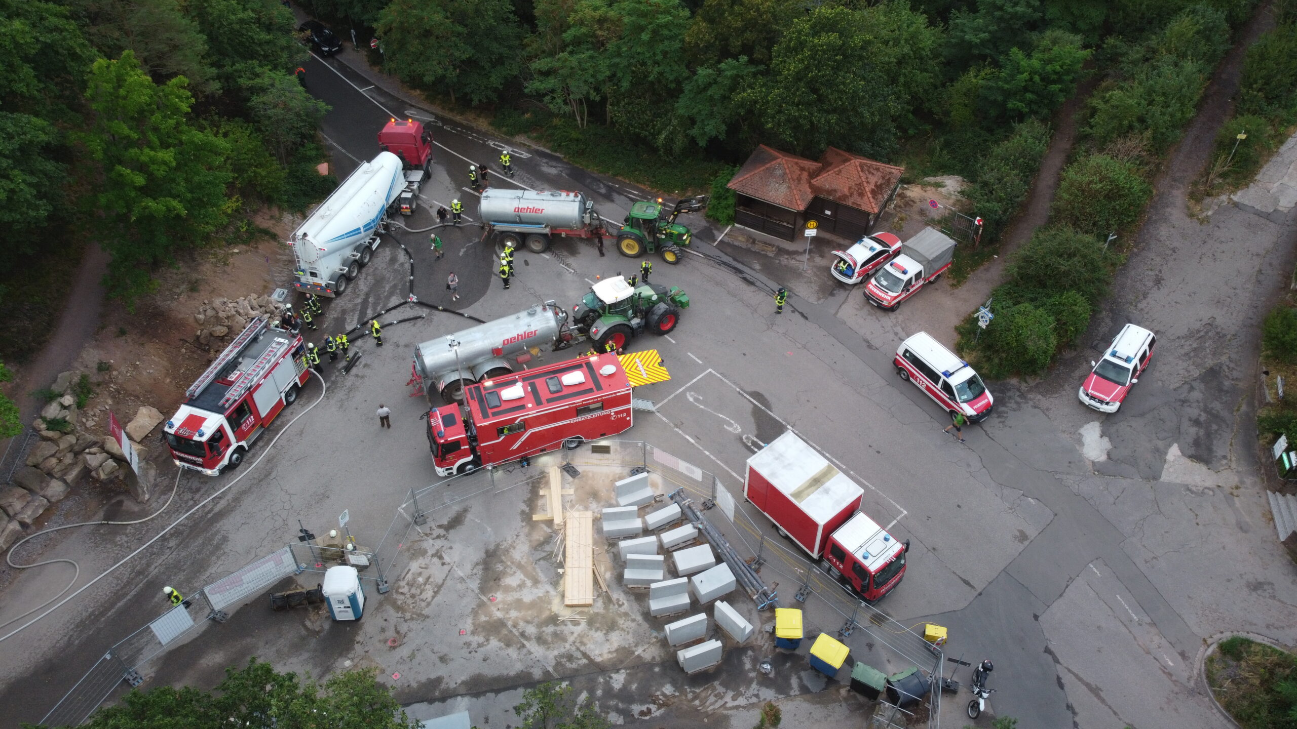 Drohnenaufnahme eines Einsatzes mit Feuerwehr, Polizei, Traktoren mit Güllefässern und mehreren Einsatzfahrzeugen an einer Straßenkreuzung im Grünen
