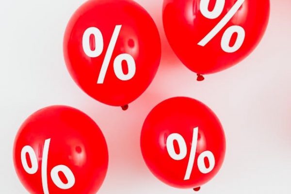 Vier Rote Luftballons mit weißen Prozentzeichen darauf, schweben vor einem weißen Hintergrund